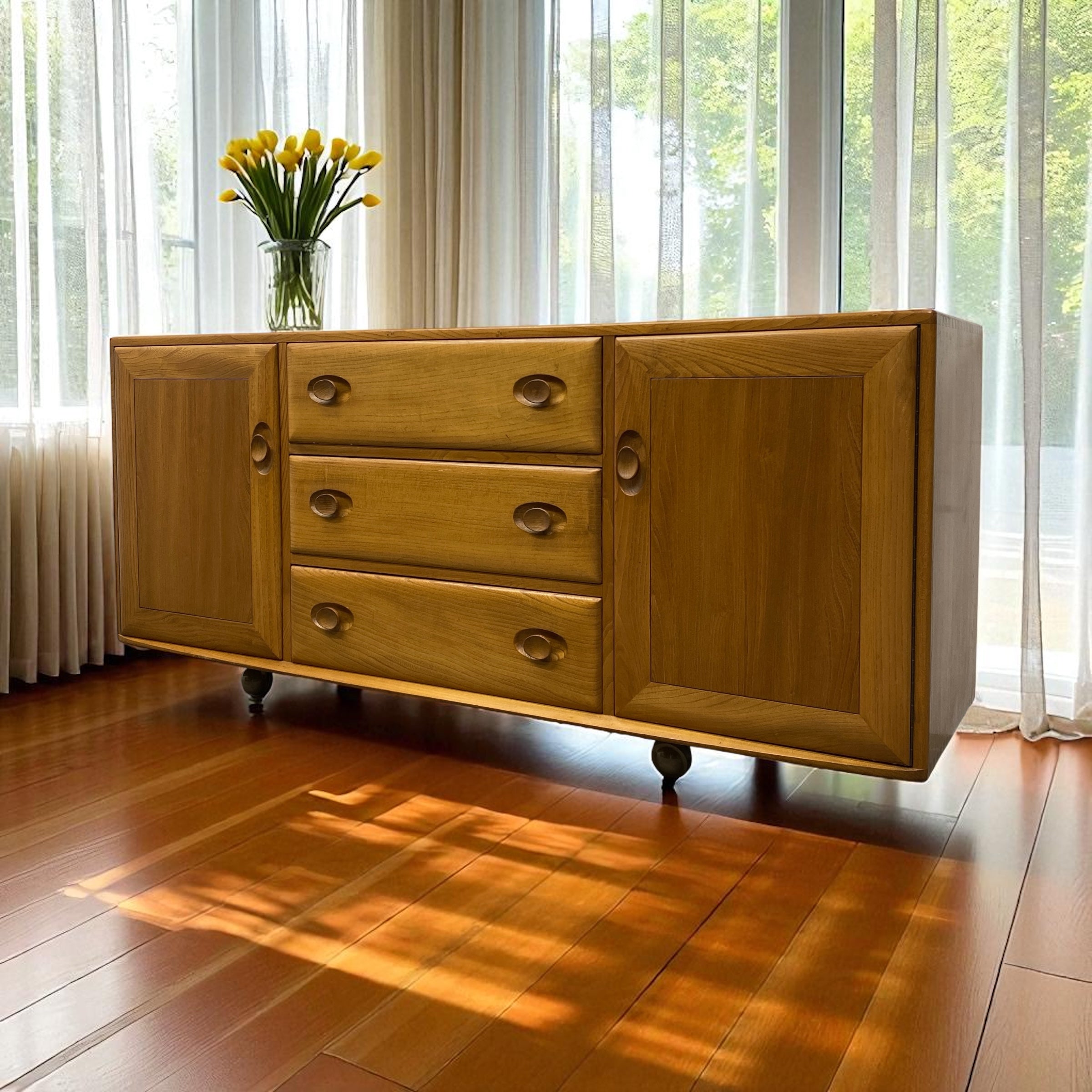 Wooden sideboard with drawers and a vase of yellow tulips on a wooden floor.