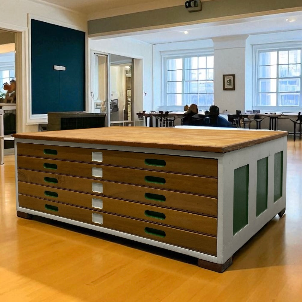 Large wooden PLAN CHEST with drawers in a room with large windows.
