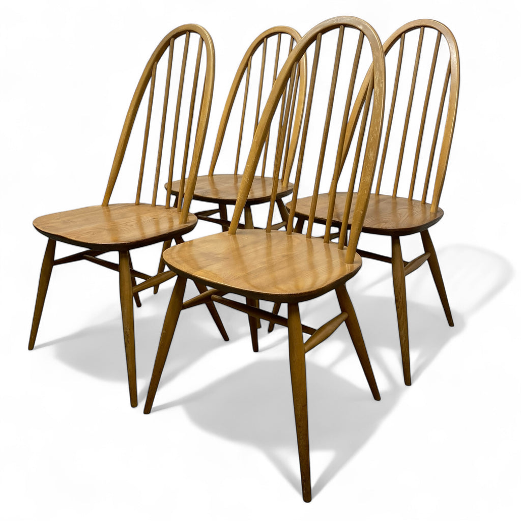 Four wooden chairs with spindle backs on a white background