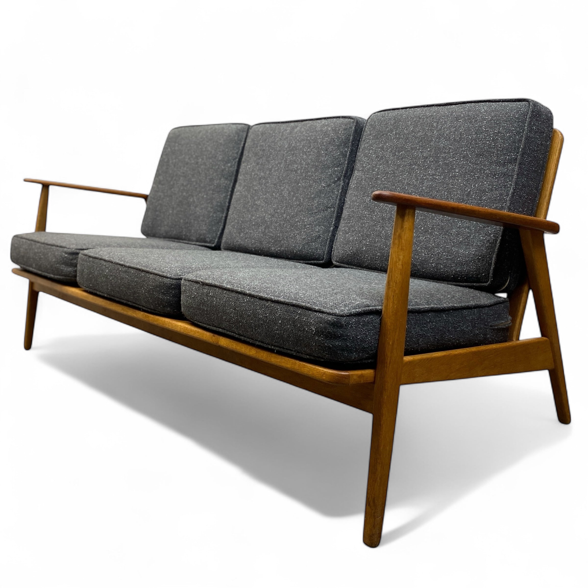 Three-seater sofa with wooden frame and grey cushions on a white background