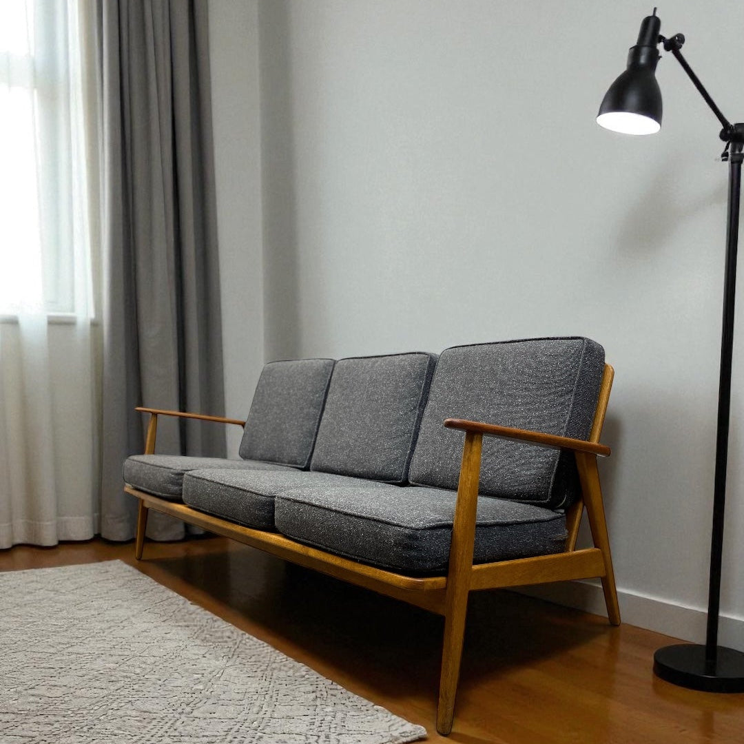 Grey sofa with wooden frame in a room with a lamp and curtains.