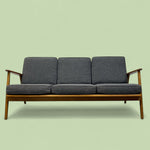 Load image into Gallery viewer, Grey sofa with wooden arms on a light green background
