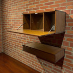 Load image into Gallery viewer, Wooden wall-mounted drinks cabinet with open surface against a brick wall.
