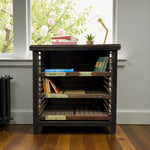 Load image into Gallery viewer, Wooden bookshelf with books and a lamp against a window with floral decorations
