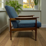 Load image into Gallery viewer, Blue armchair with wooden frame in a room with a window and plants

