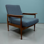 Load image into Gallery viewer, Blue upholstered armchair with wooden frame on a light gray floor and blue wall background
