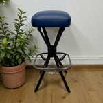 Load image into Gallery viewer, Blue stool with black metal frame on a wooden floor next to a potted plant.
