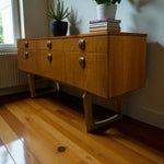 Load image into Gallery viewer, Wooden sideboard with six drawers on a wooden floor, with books and a plant on top.
