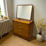 Load image into Gallery viewer, Wooden dresser with mirror next to a radiator and a vase of yellow flowers on a wooden floor.
