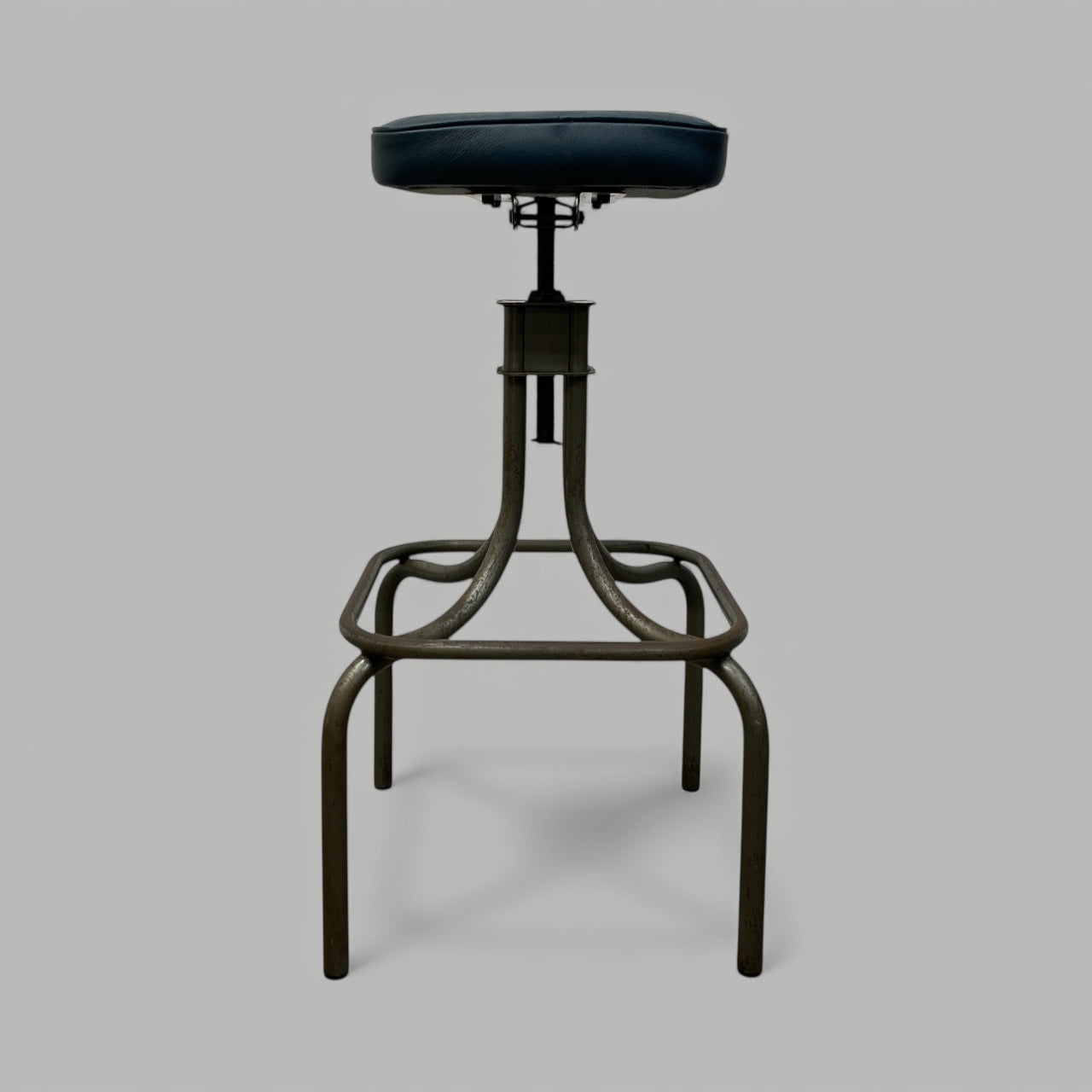 Vintage-style stool with black leather seat on a gray background