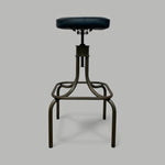 Load image into Gallery viewer, Vintage-style stool with black leather seat on a gray background
