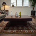 Load image into Gallery viewer, Living room with a wooden coffee table, cleaning products, and a plant.
