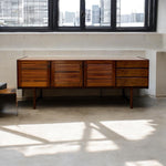 Load image into Gallery viewer, Wooden sideboard with slatted doors in a room with large windows.
