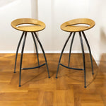 Load image into Gallery viewer, Two wooden stools with black metal legs on a wooden floor.
