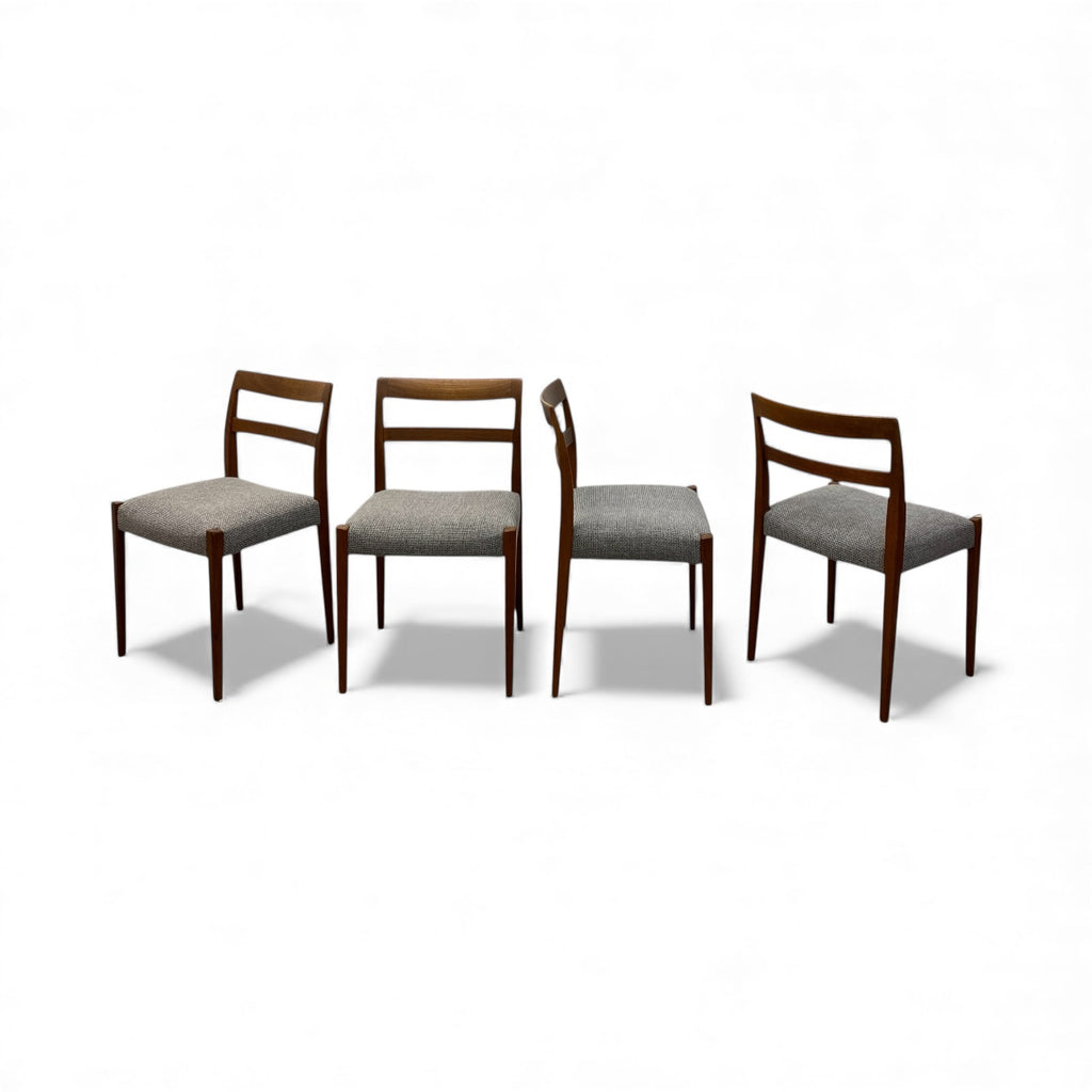Four wooden chairs with gray seats on a white background