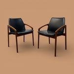 Load image into Gallery viewer, Two black leather chairs with wooden frames on a beige background
