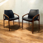 Load image into Gallery viewer, Two black chairs with wooden frames on a wooden floor.
