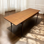 Load image into Gallery viewer, Wooden dining table in a room with light curtains and a tiled floor.
