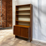 Load image into Gallery viewer, Wooden bookshelf with a cabinet against a white wall.

