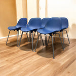 Load image into Gallery viewer, Four blue chairs with black legs arranged on a wooden floor.
