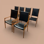 Load image into Gallery viewer, Set of five black chairs with wooden frames on a beige background
