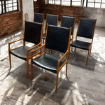 Load image into Gallery viewer, Set of black chairs with wooden frames in a rustic indoor setting
