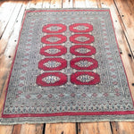 Load image into Gallery viewer, Decorative rug with red and gray pattern on a wooden floor
