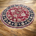Load image into Gallery viewer, Round floral-patterned rug on a wooden floor
