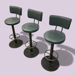 Load image into Gallery viewer, Three green bar stools with backrests on a light purple background
