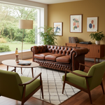 Load image into Gallery viewer, Living room with reddish brown leather sofa, green armchairs, and framed art on a mustard wall.
