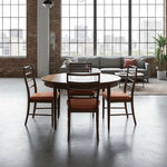 Load image into Gallery viewer, Dining area with round table and chairs in a modern living room with large windows.

