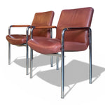 Load image into Gallery viewer, Two brown leather chairs with metal frames on a white background
