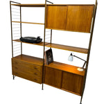 Load image into Gallery viewer, Wooden shelving unit with drawers and a lamp on a white background
