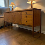 Load image into Gallery viewer, Wooden sideboard with circular designs and drawers in a room setting.
