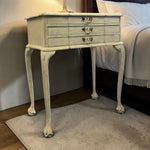 Load image into Gallery viewer, Vintage-style side table with three drawers in a bedroom setting.
