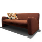 Load image into Gallery viewer, A mid-century modern terracotta brown upholstered loveseat with a patterned accent pillow, shown on a white background with a soft shadow.
