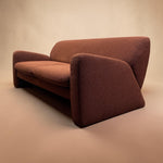 Load image into Gallery viewer, A mid-century modern loveseat sofa upholstered in a textured rust-brown fabric, shown from a three-quarters angle against a warm beige studio background.
