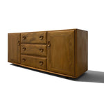 Load image into Gallery viewer, A mid-century modern wooden sideboard with three drawers on the left and two cabinet doors on the right, featuring round metal pulls, shown on a white background with a soft shadow.
