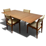 Load image into Gallery viewer, A mid-century modern wooden dining table with four matching upholstered chairs, shown on a clean white background with a soft shadow.
