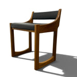 Load image into Gallery viewer, A mid-century modern wooden dining chair with a warm brown wood frame and dark gray upholstered seat and backrest, shown on a white background with a soft shadow.
