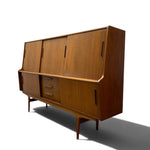 Load image into Gallery viewer, Mid-century modern wooden sideboard cabinet with a warm medium-brown wood grain finish, featuring a slanted upper cabinet door, three drawers, and tapered legs, shown on a white background with a soft shadow.
