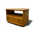 Load image into Gallery viewer, A small wooden side table or TV stand with a warm honey oak finish, featuring a single drawer with round knobs and an open shelf, shown on a white background with a soft shadow.
