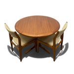 Load image into Gallery viewer, A mid-century modern round wooden dining table with a matching four-piece chair set, featuring light beige upholstered seats and backs, shown from an elevated perspective on a white background.
