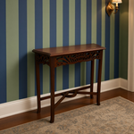 Load image into Gallery viewer, A dark brown wooden console table with decorative carved legs and a rectangular top, positioned against a blue and green striped wall in a room with hardwood floors and a patterned rug.
