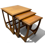 Load image into Gallery viewer, Three nested wooden nesting tables with a warm medium-brown finish and curved open-frame legs, shown on a white background with a soft shadow.
