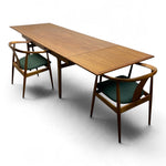 Load image into Gallery viewer, A mid-century modern wooden dining table with extendable leaves, accompanied by two matching wooden chairs with green upholstered seats, shown on a white background.
